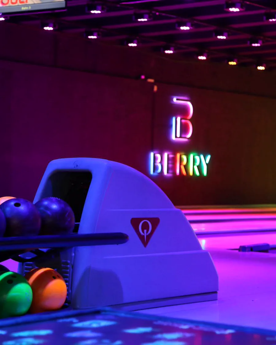 Bowlingbereich mit Bowlingkugeln und beleuchtetem BERRY Logo